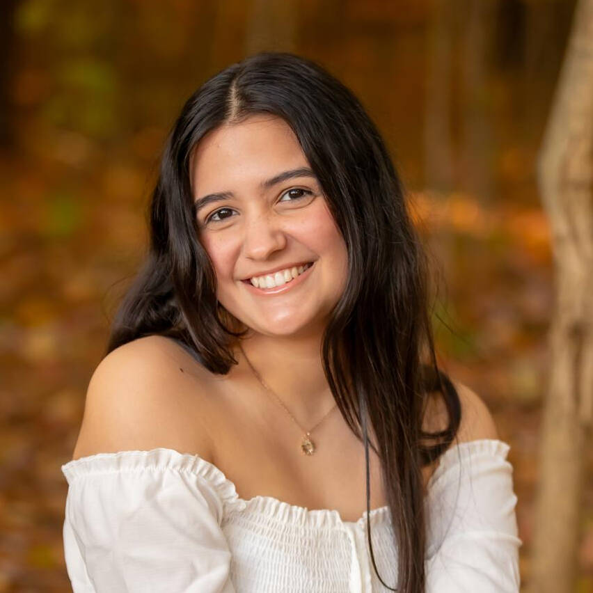 Smiling young woman with dark hair against an out of focus nature background